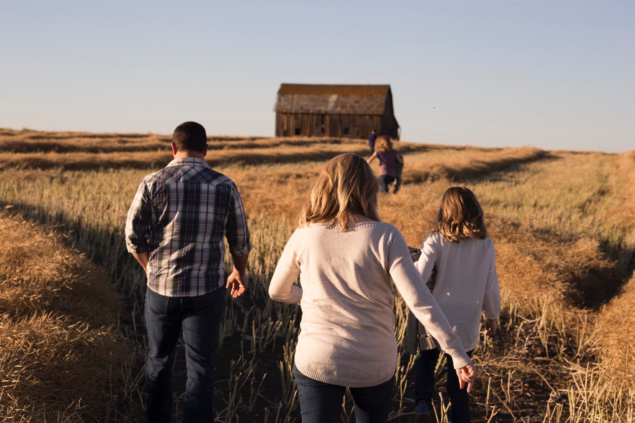 A family with a mum, dad and three children, walking towards a barn in an open field