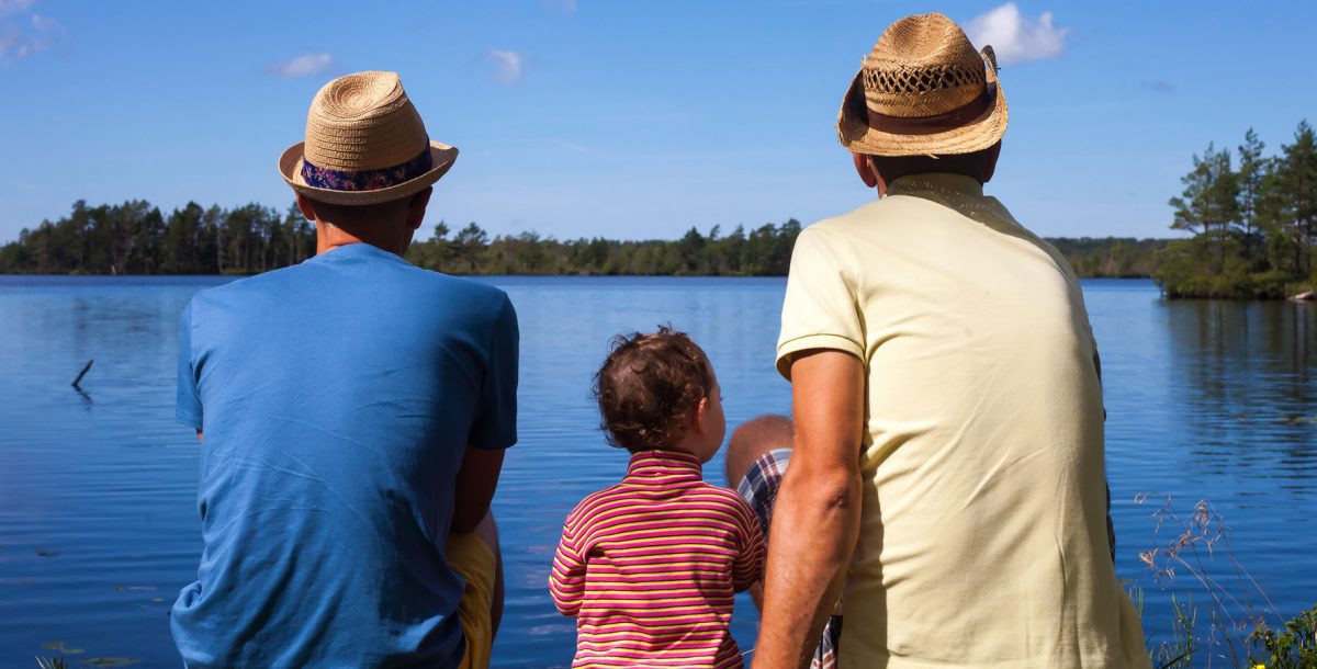 two dads and thier child looking out onto a lake