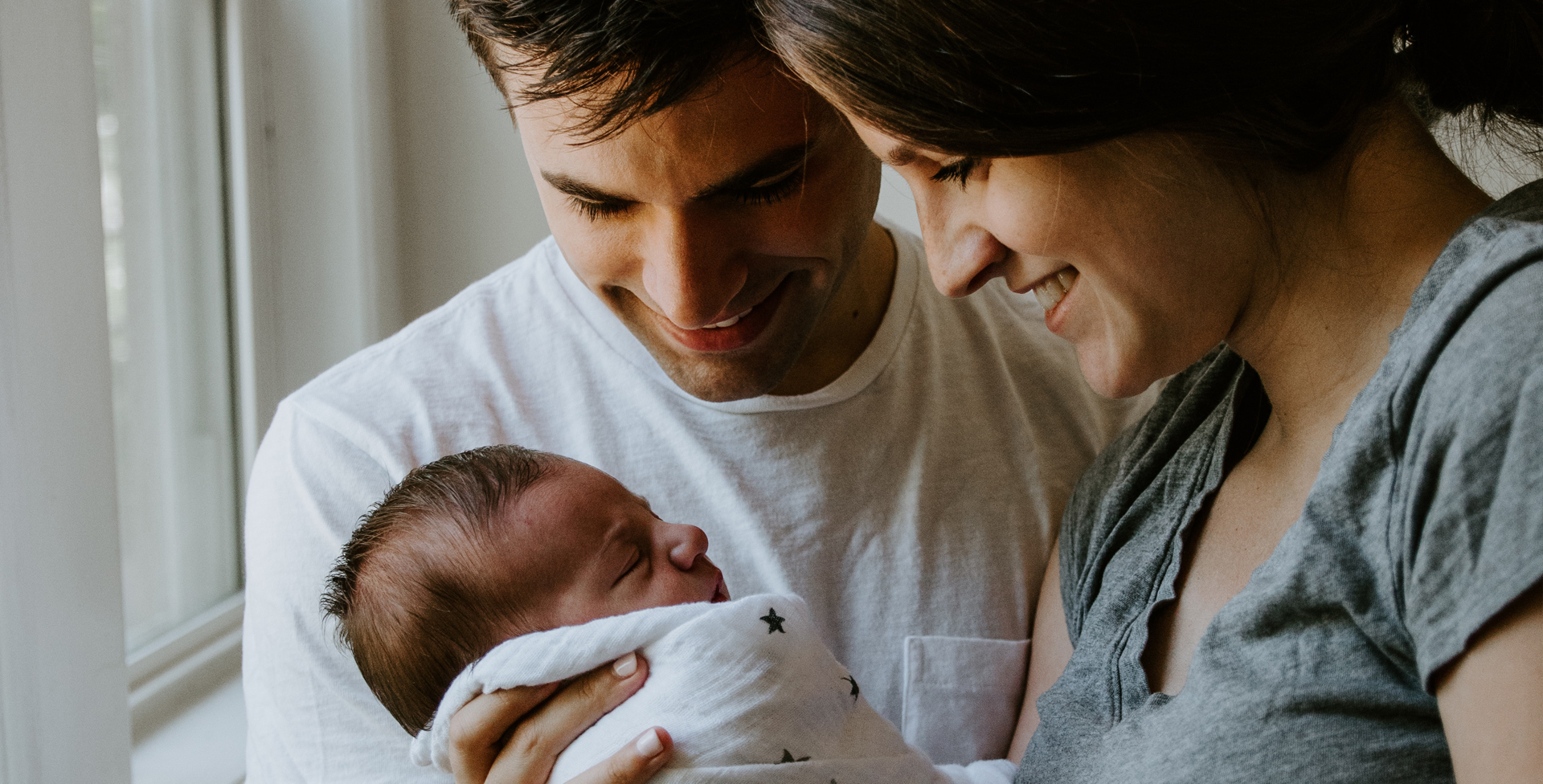 a mother and fathers looking happily at their newborn