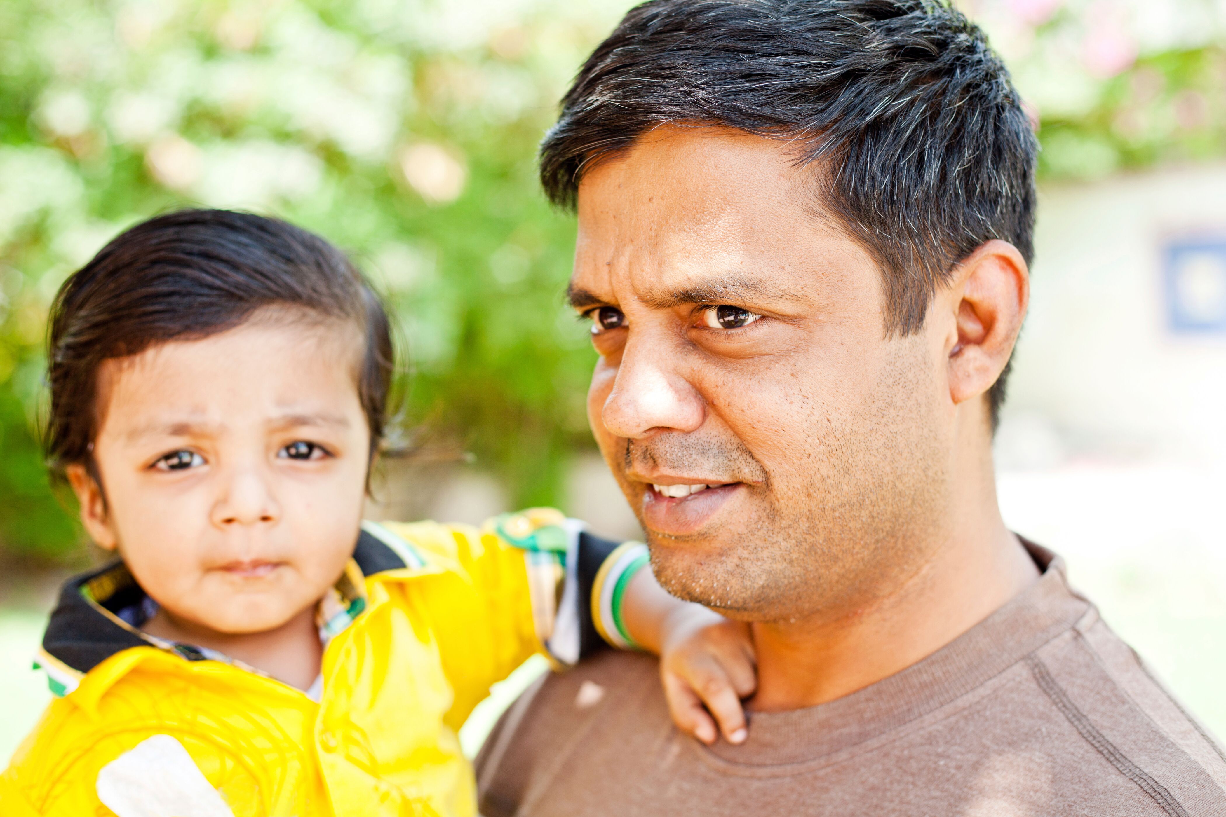 a dad holding his young child in his arms looking at the camera